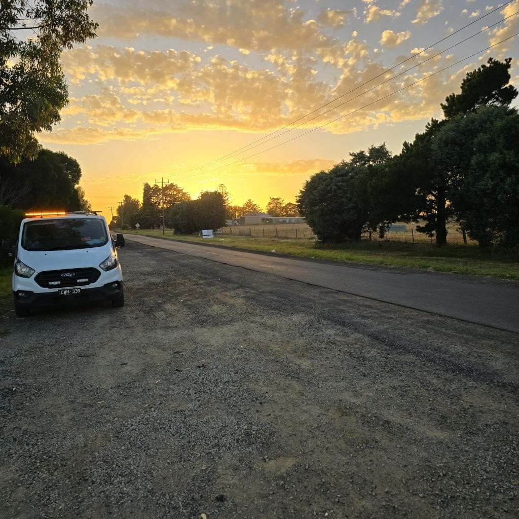 White survey van parked on gravel road during sunrise, rural setting, working in locating underground services.