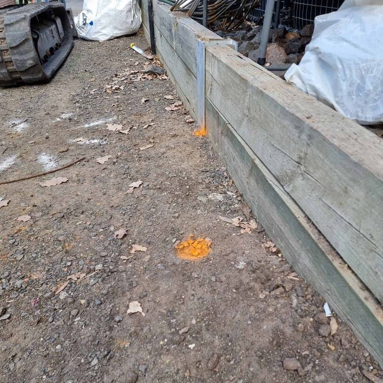 Electrical conduit running underneath a retaining wall post